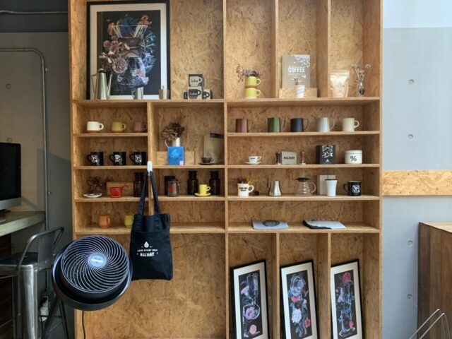 カフェの棚にはコーヒー豆やマグカップ、アート作品が並ぶ